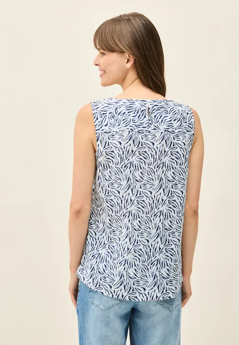Frau mit ärmellosem gemustertem Top und Jeans von hinten.
